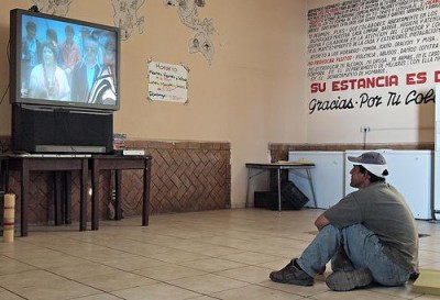 Mariano, un migrante de Honduras, mira television en Belen, Posada del Migrante. Foto de LatinDispatch.