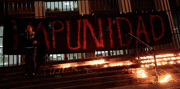 A woman stands in front of a banner reading "Impunity" in Guatemala City. Photo: REUTERS/Jorge Dan Lopez