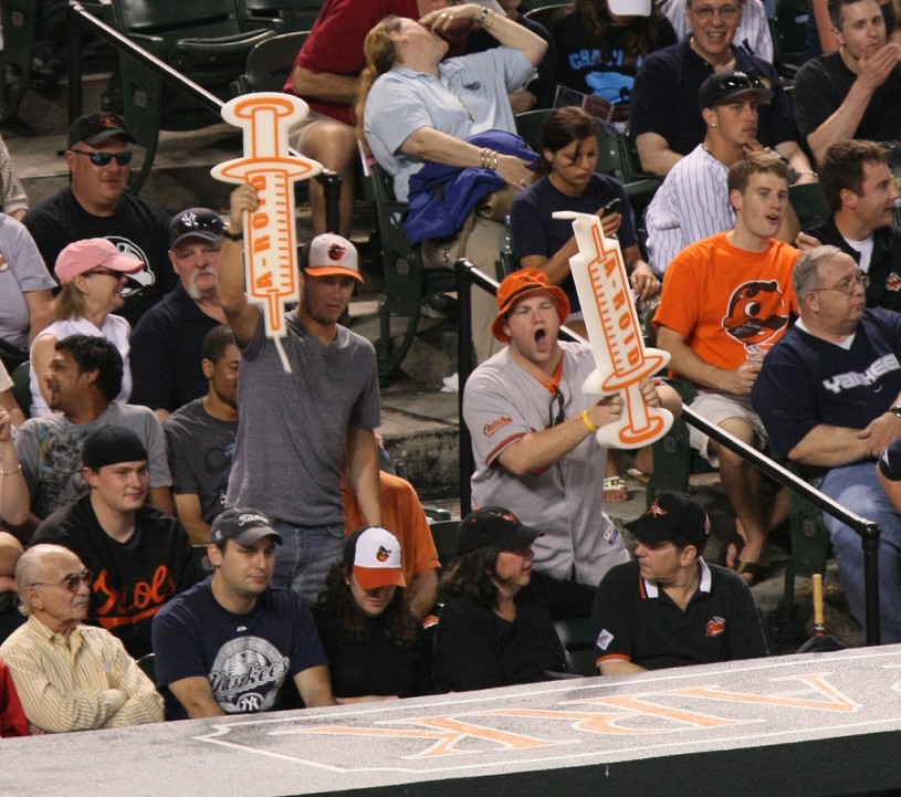Sports fans holding steroid syringe signs