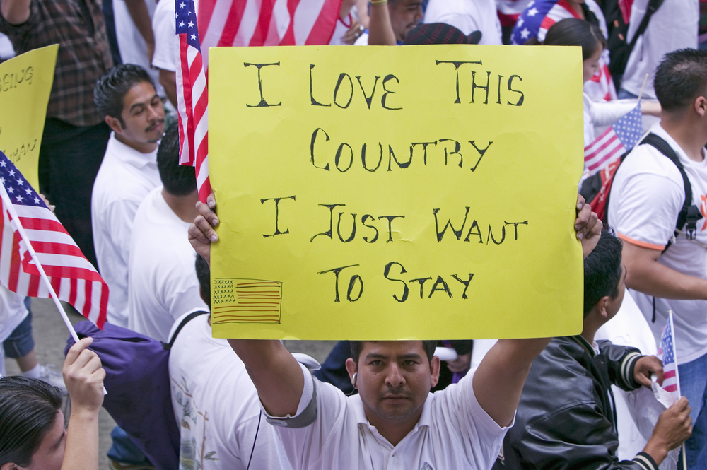 Man holding sign at an immigration rally reading "I love this country, I just want to stay"