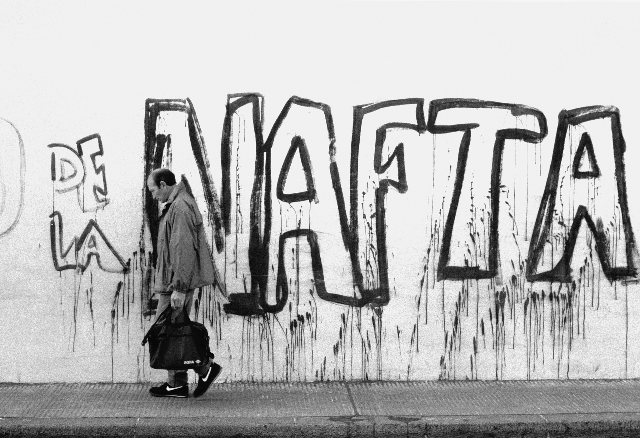 man in nikes in front of NAFTA graffiti