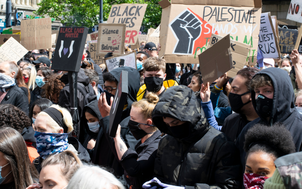 Manchester UK. June 6 2020. Black Lives Matter protest in Piccadilly Gardens. Large crowd march with cardboard placards in front of city shops