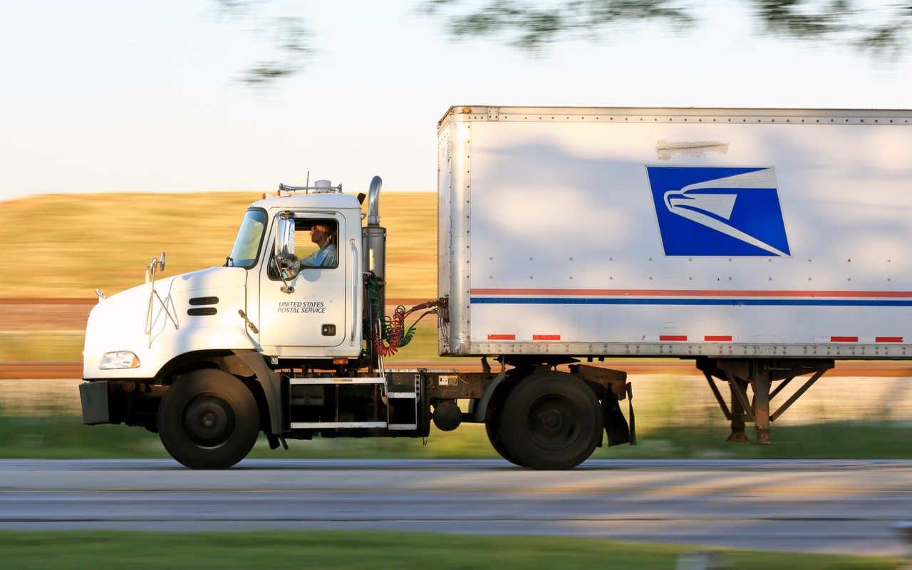 postal service worker driving a delivery truck