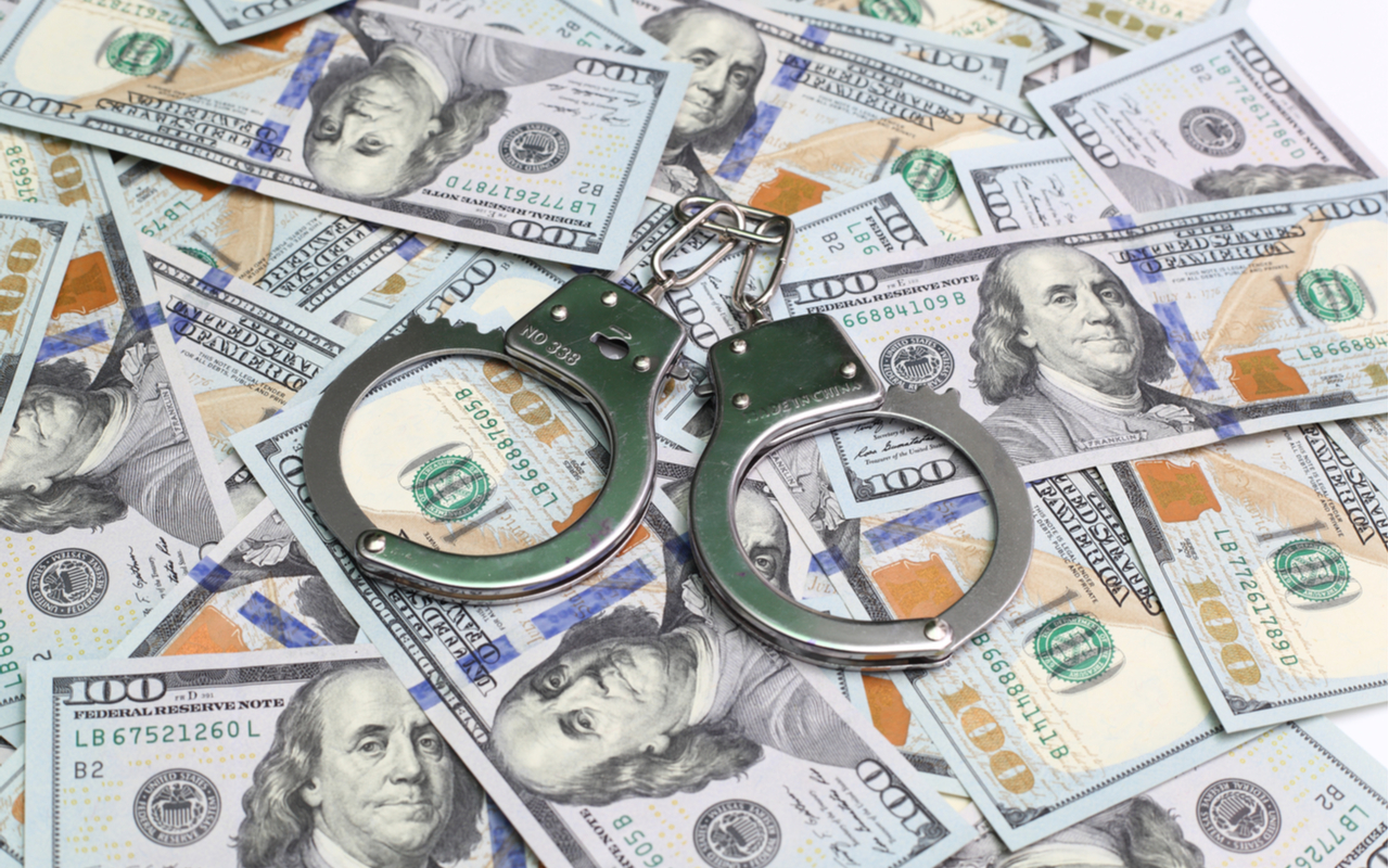 money and handcuffs to depict tax avoidance - taxation - tax evasion