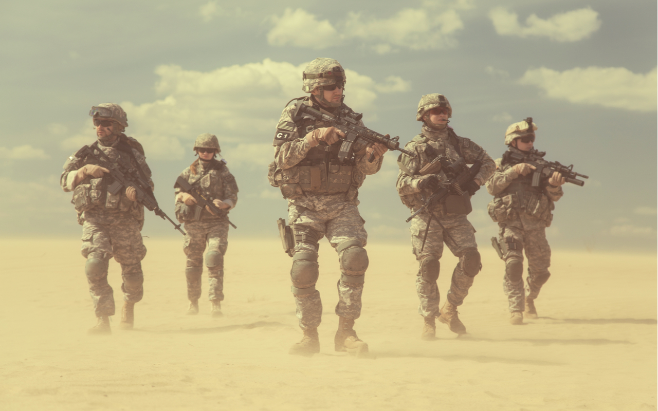 u.s. military soldiers armed and patrolling a sandy aread resembling a desert