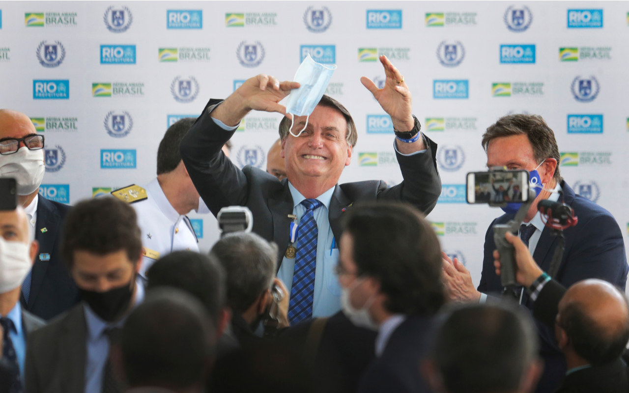 Brazilian president jair Bolsonaro holds a mask as waves to the followers during a ceremony
