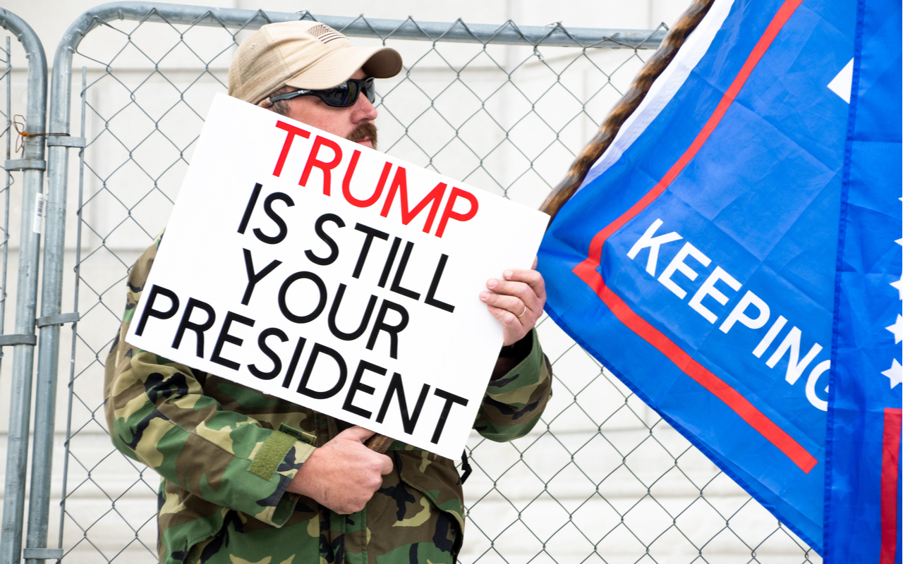 trump supporter holding a sign that says trump is still your president