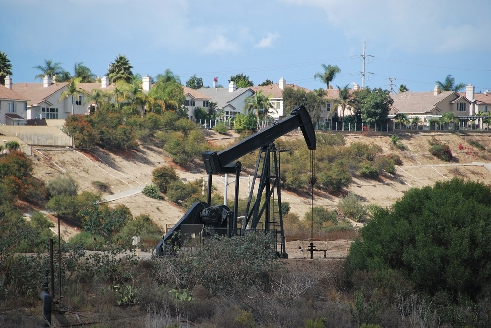 A pumpjack derrick drills for oil right next to a Los Angeles neighborhood