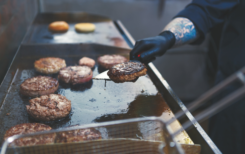 person cooking burgers on a grill