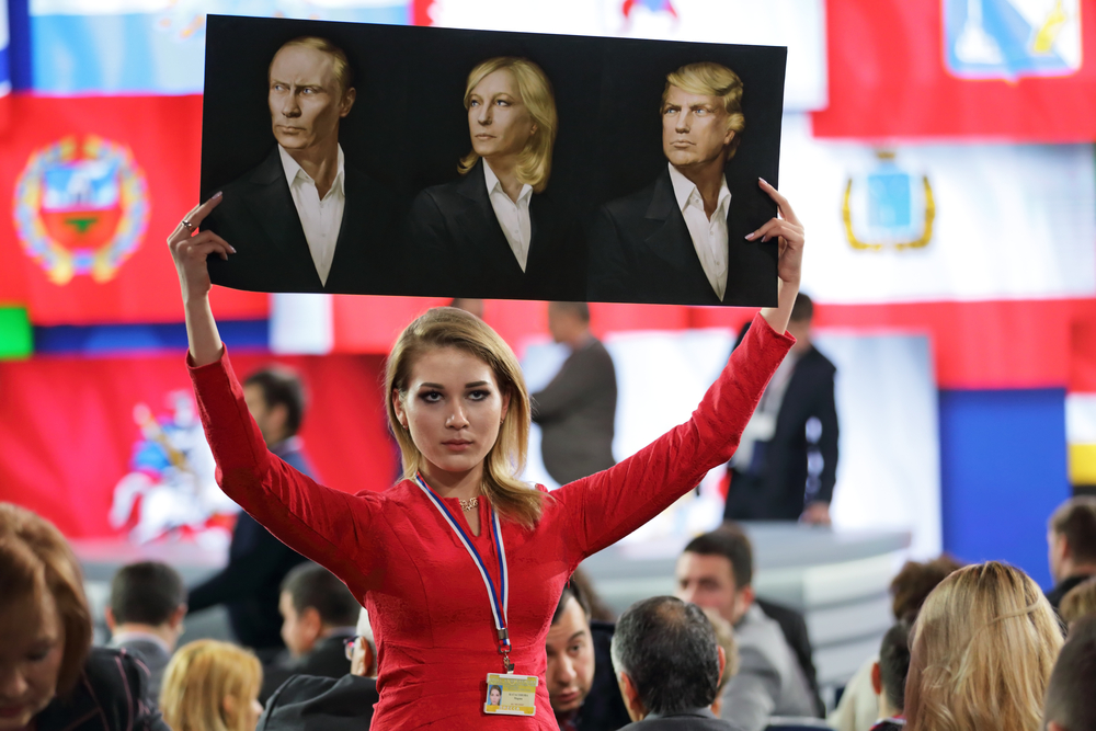 An activist of the National Liberation Movement Katasonova Maria holds a poster with the image of Vladimir Putin, Marine Le Pen, and Donald Trump at the press conference of the President of Russia