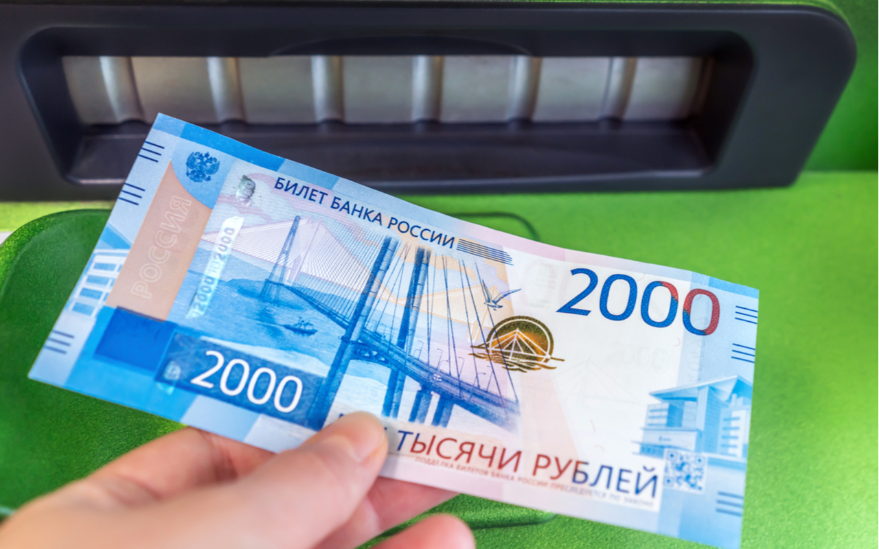hand holding a 2000 russian rubles bank note near an ATM machine