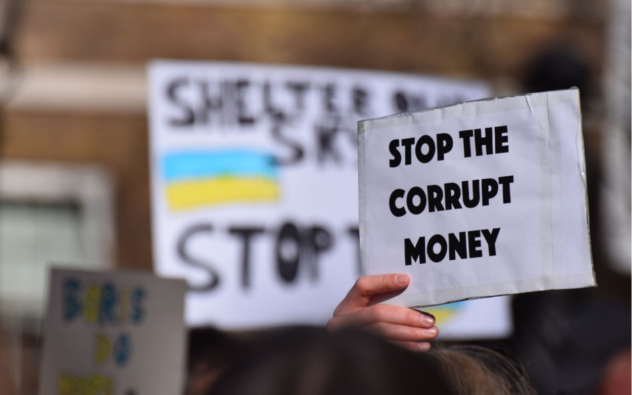 protester holding a sign that says stop the corrupt money