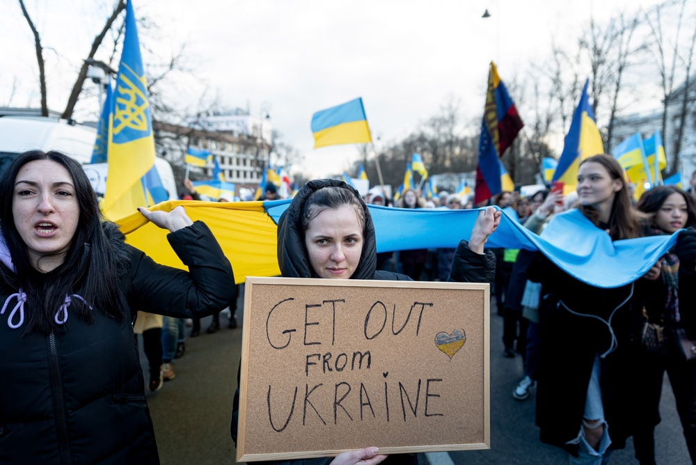 protester holding a sign that says get out from Ukraine