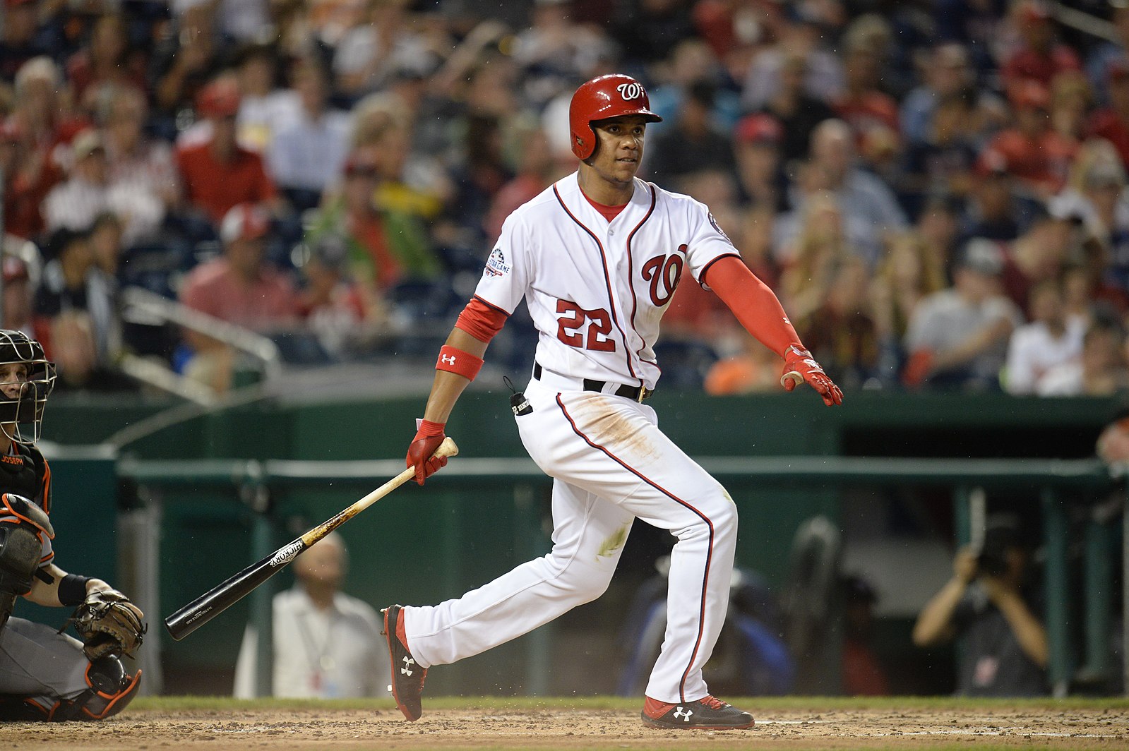 Photo of Juan Soto in red and white baseball jersey and helmet, in motion with a baseball bat in his right hand.