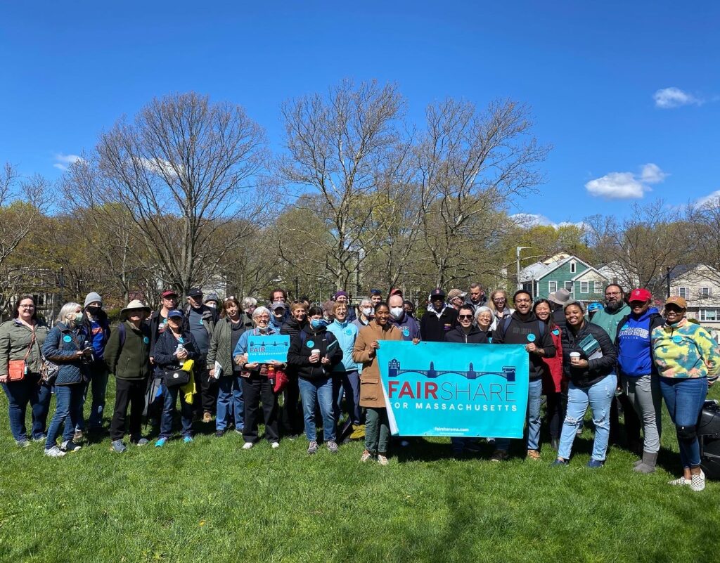 Image of Massachusetts voters at a rally, holding signs that read "Fair Share Massachusetts."
