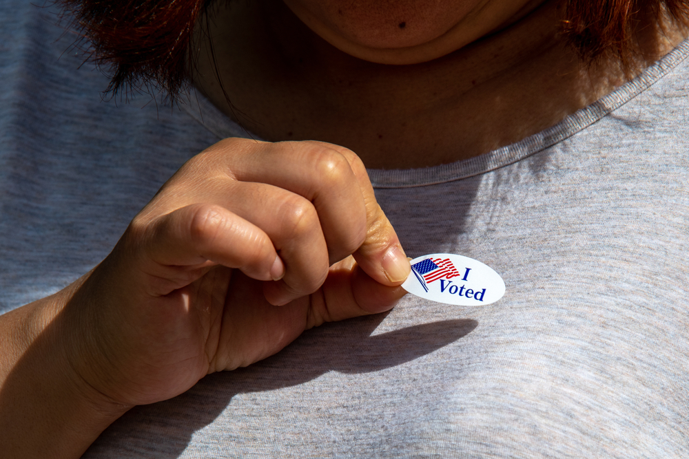 A woman places an "I voted" sticker on her shirt.