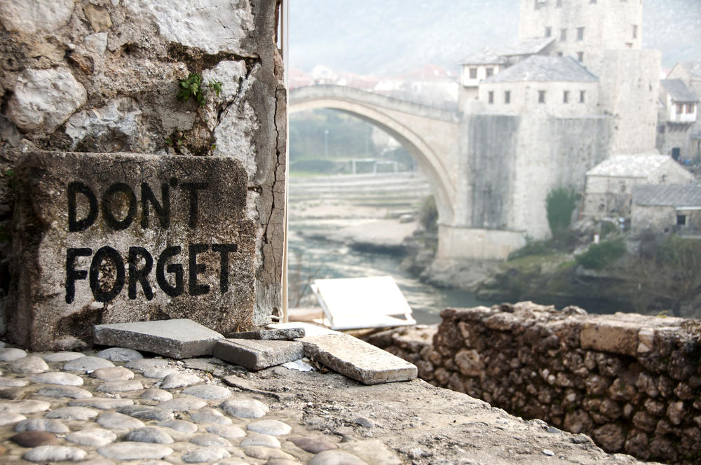 Image of Mostar bridge with stones in the foreground that read "Don't forget."