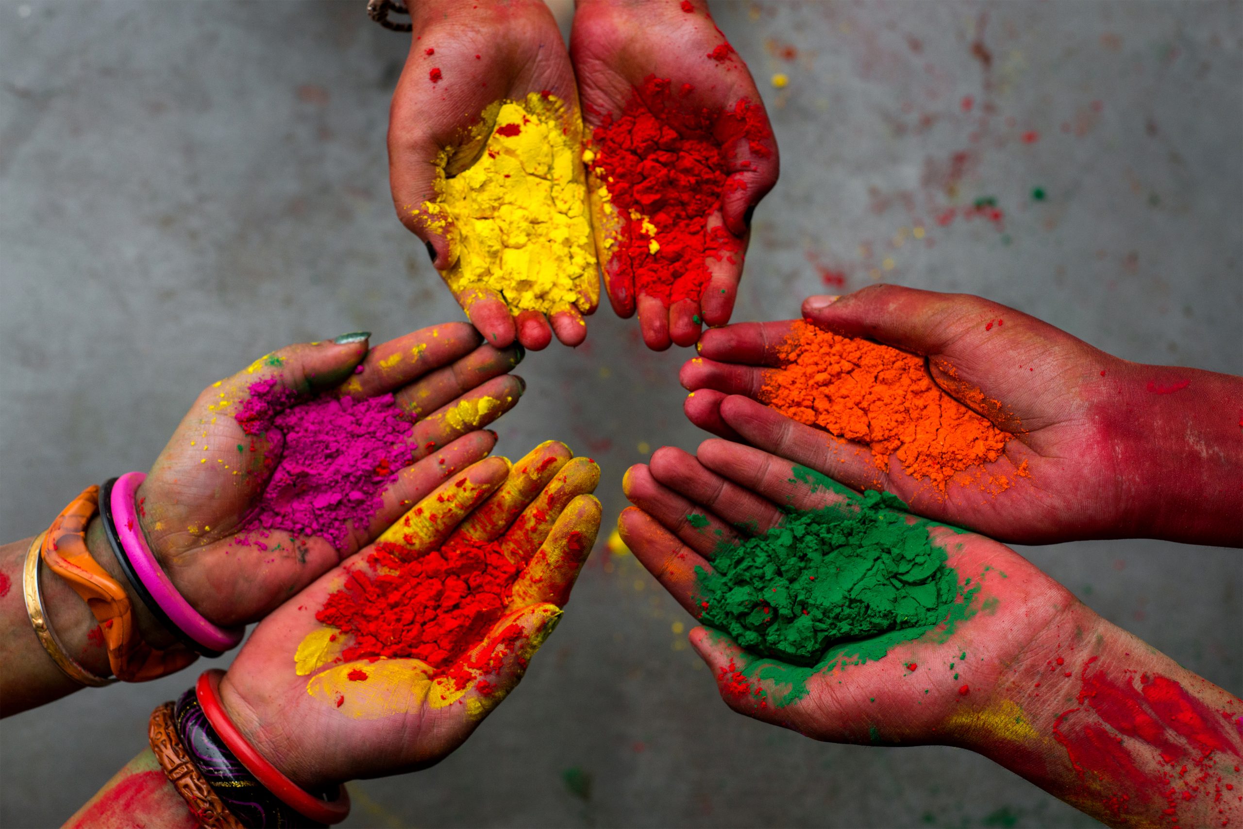 Some hands showing color powder during Holi festival in India.