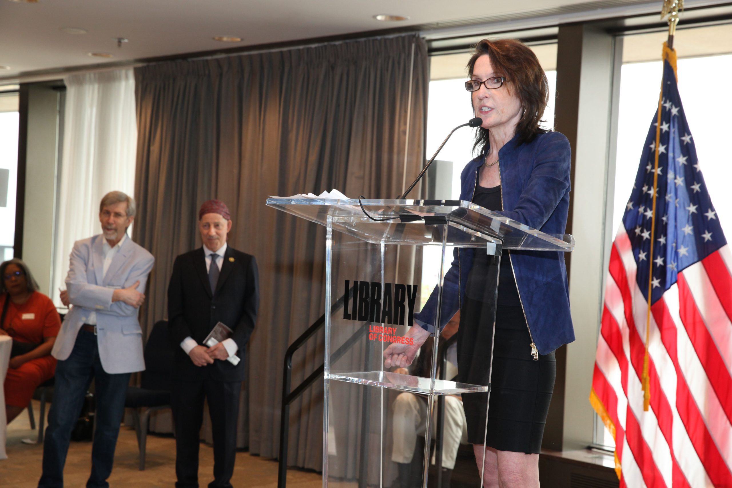 Katrina vanden Heuvel accepts the 2023 Marc Raskin Award for Civic and Intellectual Courage. IPS Senior Adviser John Cavanagh (left) and Rep. Jamie Raskin (right) look on in the background.