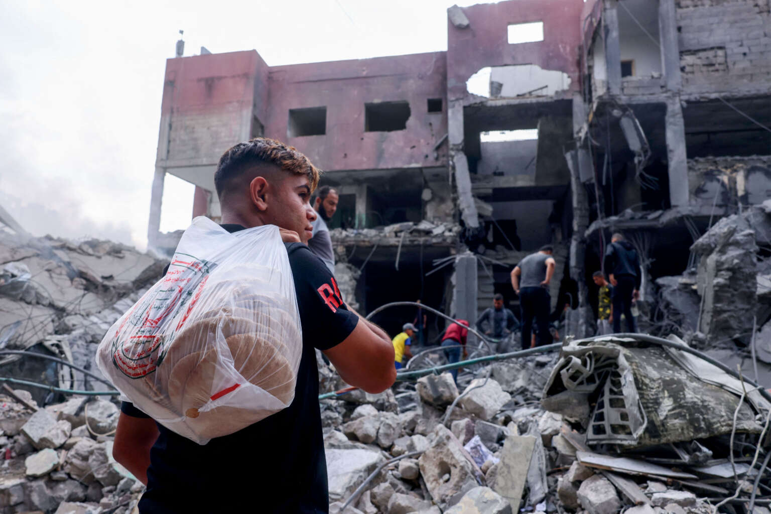 A Palestinian youth carries bread amid the rubble of the city center of Khan Yunis in the southern Gaza Strip following Israeli shelling on October 10, 2023.